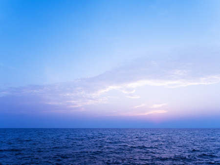 Peaceful serene sea scape and blue tone sunset or sunrise sky with clouds, tropical island ocean view at dawn or duskの写真素材