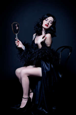 Retro burlesque diva in black corset, posing with a mirrorの写真素材