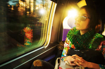 Candid shot of a young beautiful Parisian woman traveling in a train, sitting near the window
