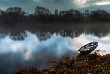 Boat on lake with a reflection in the water at sunsetの写真素材