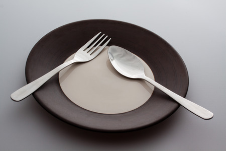 Plates with a silver fork and spoon isolated on gray background meaning pauseの写真素材