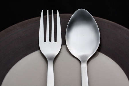 Plates with a silver fork and spoon isolated on black  background.