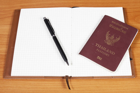 open notebook with passport and pen over wooden backgroundの写真素材