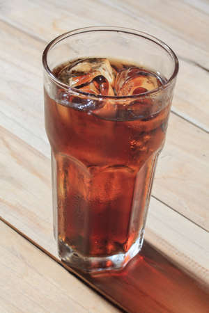 glass of cola with ice on woodの写真素材