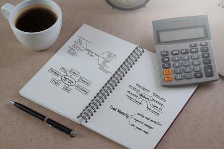 closeup of a notebook with text written in it and a cup of coffee on a wood table