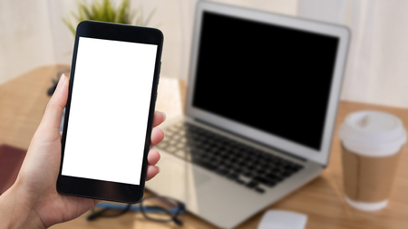 Woman hand holding smart phone on background workplace tableの写真素材
