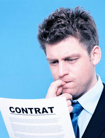 businessman reading a contract with finger in a mouthの写真素材