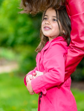 Summer portrait of pretty little girl in the arms of his motherの写真素材