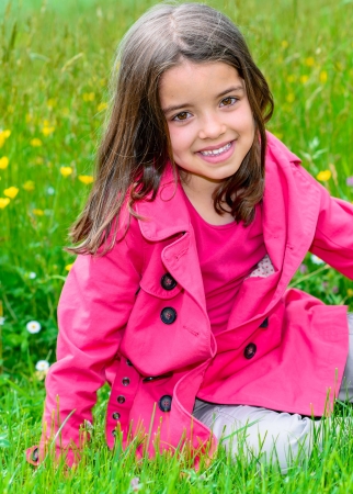 Summer portrait of happy cute child sitting in a grass of a flower gardenの写真素材