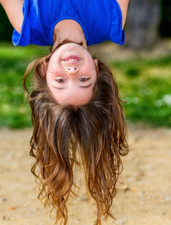 beautiful child hanging upside with greenery in the backgroundの写真素材