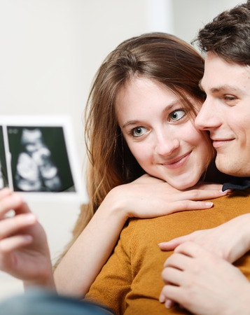 Beautiful couple watching with emotion ultrasound pictures of their babyの写真素材