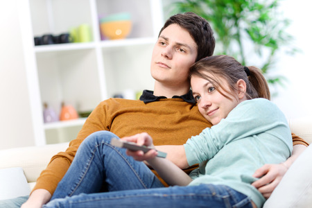 Lovers watching tv in the living room at homeの写真素材