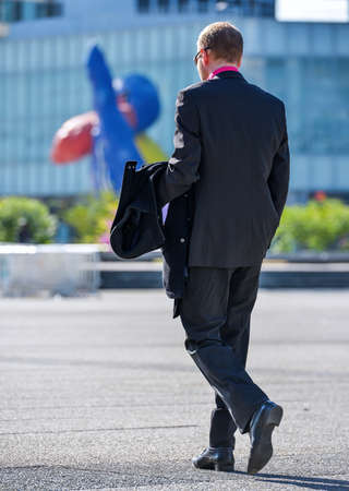 Back view of business traveler man walking with suitcase in the streetの写真素材