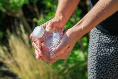 Closeup of woman crushing a plastic bottle