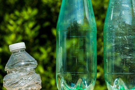 Three plastic bottles with one bottle crushed to illustrate recyclingの写真素材