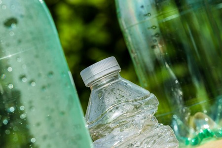 Three plastic bottles with one bottle crushed to illustrate recyclingの写真素材