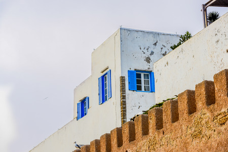 A tall white building surrounded by battlement style brick gateの写真素材
