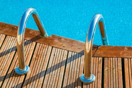 Blue swimming pool with teak wood flooring stripes summer vacationの写真素材