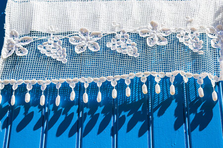 beautiful white lace curtains on a blue wooden shutterの写真素材