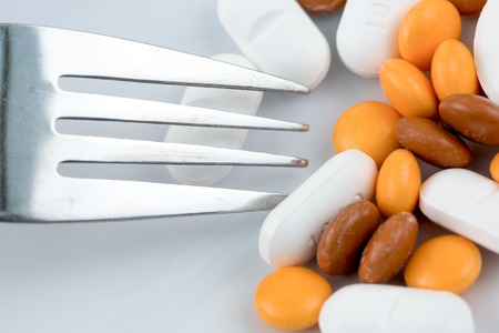 Picking medicine from a plate with silver forkの写真素材