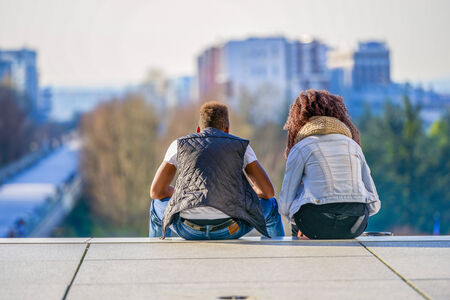 A couple adimiring the city landscape sitting on a high staircaseの写真素材