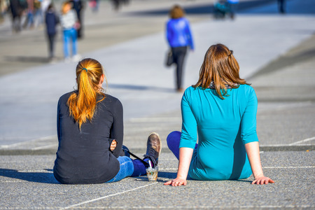 Two girls chilling out on the ground with an empty ice-cream cup next to themの写真素材