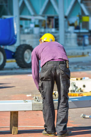 A man in purple blouse and yellow helmet working on constructionの写真素材