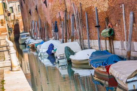 Boats with tarpaulin in romantic narrow canal in Venice.のeditorial素材