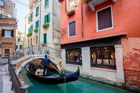 VENICE, ITALY - MAR 19 - Gondolas with tourists on Romantic narrow canal on Mars 19, 2015 in Venice, Italy.のeditorial素材