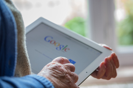 Paris, France - April 27, 2015: Senior woman using tablet with Google search home page on a ipad...