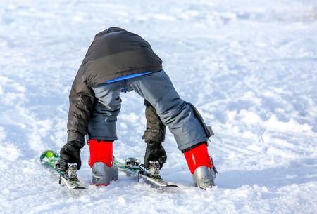 GERARDMER, FRANCE - FEB 16 - Young child putting on his ski in snow during the annual winter school holiday on Feb 16, 2015 in Gerardmer, France.のeditorial素材