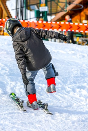 GERARDMER, FRANCE - FEB 16 - Young child putting on his ski in snow during the annual winter school holiday on Feb 16, 2015 in Gerardmer, France.のeditorial素材
