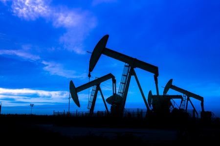 Silhouette of Oil pumps at oil field with nice sunset sky background