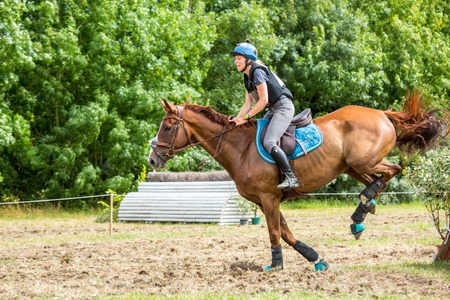 Saint Cyr du Doret, France - July 29, 2016: Woman riding horse over obstacle on cross country eventのeditorial素材
