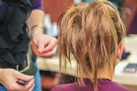 Hairdresser applying hair gel to create a sophisticated hairstyle for a weddingの写真素材