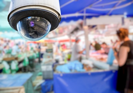 security CCTV camera or surveillance system with local market on blurry background