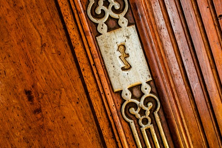 Vintage copper keyhole decorative element on weathered wooden surfaceの写真素材
