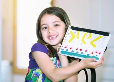 Portrait of a beautiful girl showing her drawingの写真素材