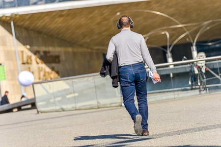 La defense, France- April 10, 2014:Back view of a young man with headphones listening to music in...