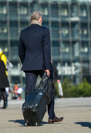 La defense, France- April 09, 2014: mature business traveler walking down the street and pulling suitcaseのeditorial素材