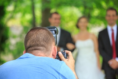 Wedding photographer in action, taking a picture of the bride and groomの写真素材