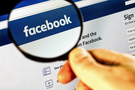 Paris, France - January 03, 2017 : Photo of Facebook homepage on a monitor screen through a magnifying glass.のeditorial素材