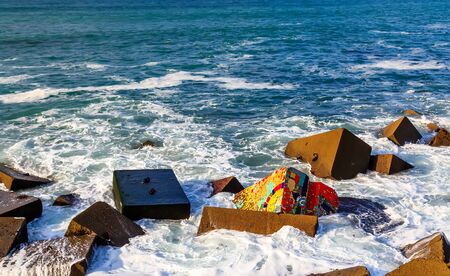 Seascape with coloreful rocks, foam and spray of the wavesの写真素材