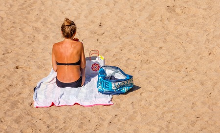 Saint-Jean de Luze, France - Sept 28, 2016: back view of amazing girl lying on the beach in the sand, wearing a black bikiniのeditorial素材