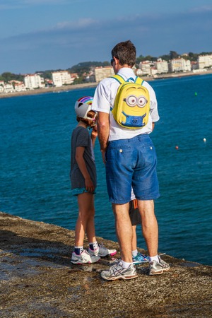 Ciboure, France - Sept 26, 2016: family of single father and two boy children sons standing on the pier of ciboure harbor.のeditorial素材