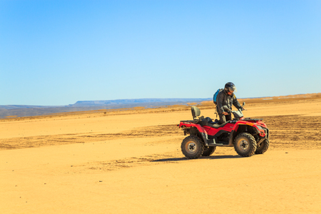 Ait Saoun, Morocco - February 22, 2016: Man riding atv quad bike on sand in desert on a sunny day in Ait Saoun desert in Morocco.のeditorial素材