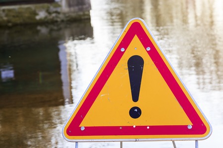 Closeup on warning sign of danger in front of a flooded roadの写真素材