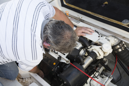close-up of a man repairing a boat engine under sunny dayの写真素材