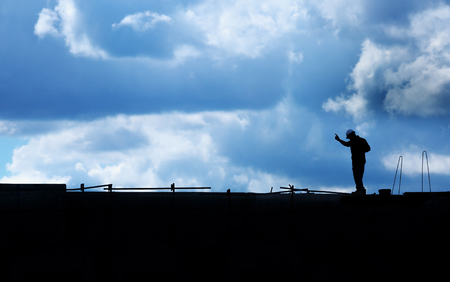 building workers working on a building under a cloudy blue sky. Chinese shadow effect.の写真素材