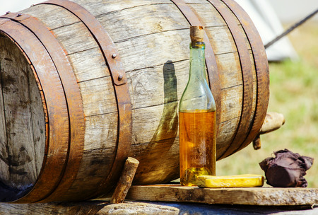Closeup of vintage wooden barrrel and cider bottle on table at outdoorの写真素材